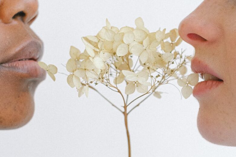 people holding white flowers close to their lips