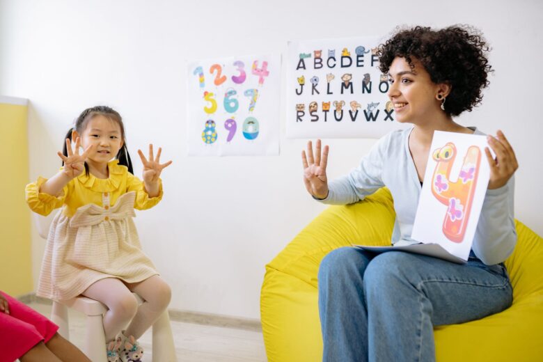 girl in yellow long sleeve dress learning to count with her teacher
